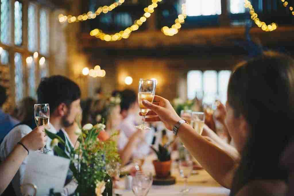 Members toasting at a dinner table with string lights